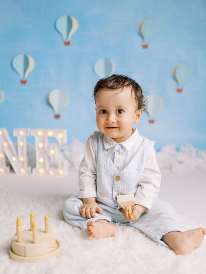 A baby boy playing with a wooden cake toy in a beautifully styled studio setup. A great alternative to a real cake for some sessions.
