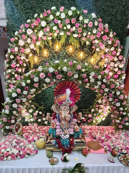 A truly grand floral arch for a beloved Ganpati idol. This massive arrangement uses thousands of pink and white flowers against a green wall, with warm lights that make the entire setup look divine and welcoming.