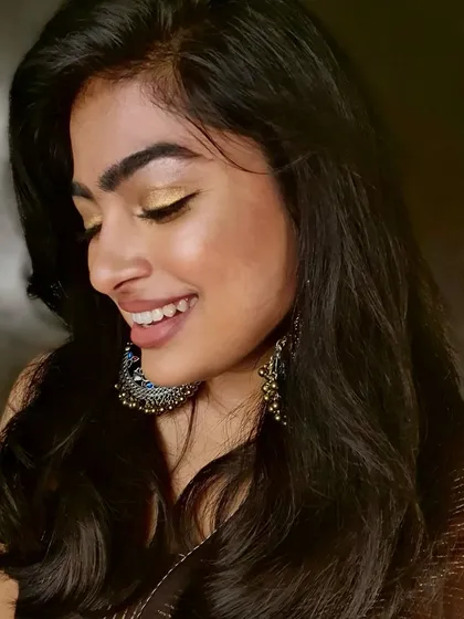 A candid moment showing how the makeup looks natural and radiant even when smiling. The glowing highlighter and soft gold eyeshadow create a happy, celebratory feel.