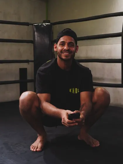 A coach smiles while relaxing in the boxing ring. Our team is approachable, friendly, and a core part of the Knox community.