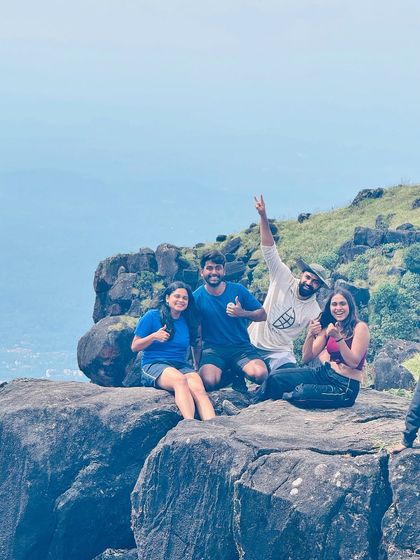 Friends enjoying the view from a rocky outcrop on the Kumara Parvatha trail. It's the perfect spot to rest, click photos, and appreciate the scenery.