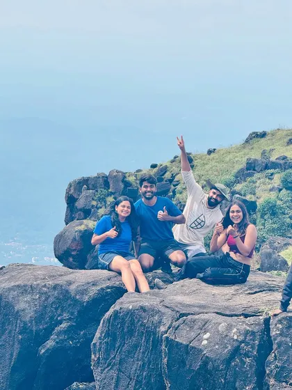 A group of friends taking a break on the rocky terrain of the Kumara Parvatha trek.