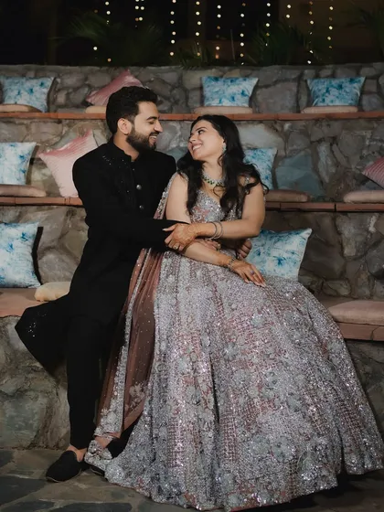 An intimate and happy portrait of a couple at their Sangeet. They are seated in a stone amphitheater, sharing a look of love under the warm evening lights.
