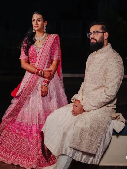 A regal portrait of our client and his bride. His custom-fit ivory sherwani is a perfect match for her elegant pink lehenga, creating a picture of royal harmony.