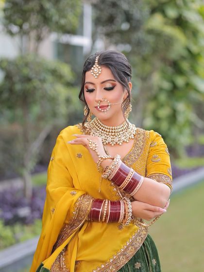Her beauty rivals the moon’s gentle glow. For this bride, I created a soft yet glamorous look with defined eyes and a nude lip to complement her vibrant yellow and green lehenga.