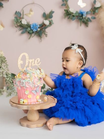 Her curiosity is sparked as she reaches for her very first birthday cake, a perfect candid moment from this milestone session.