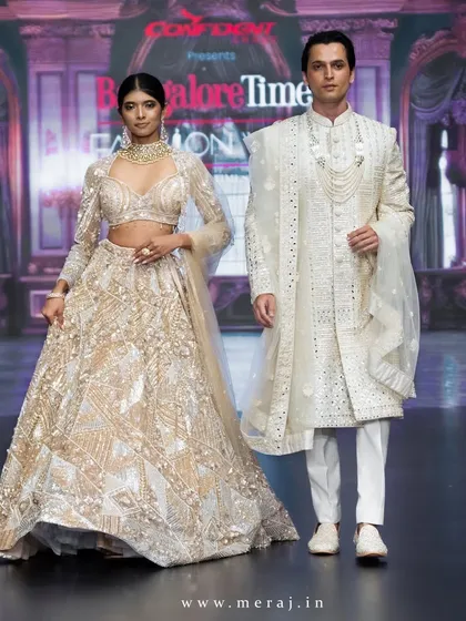 A perfect pair on the runway. This look highlights my coordinated couple's wear, with the bride in a gold geometric-designed lehenga and the groom in a matching sherwani, showcasing modern opulence and shared style.