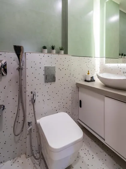 This modern bathroom uses large-format terrazzo tiles for both the floor and walls, paired with a sleek white vanity and backlit mirror for a clean, contemporary feel.
