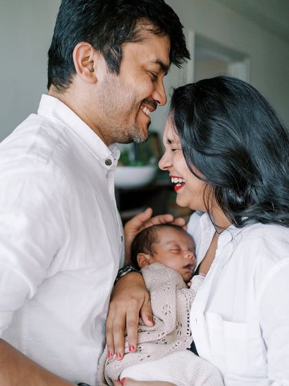 A happy family portrait with a sleeping newborn. The parents' joy is so evident.