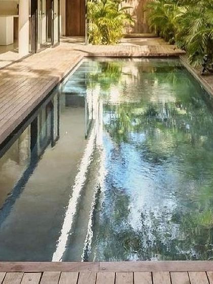 A lap pool integrated into a residential design. The wooden deck and surrounding plants create a private oasis where the home opens directly to the water.