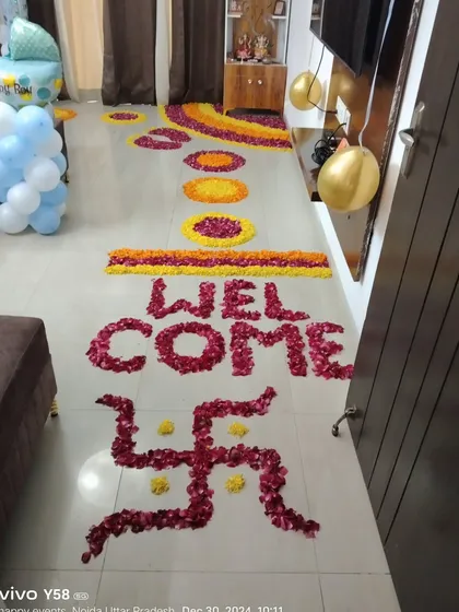 A traditional welcome home decoration using flower petal rangoli, including a swastika for blessings.