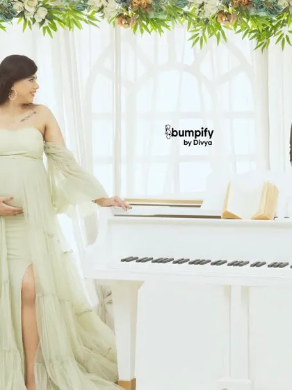The dad-to-be joins the scene, leaning on the piano and sharing a look with his partner. A romantic and sophisticated couple's shot.