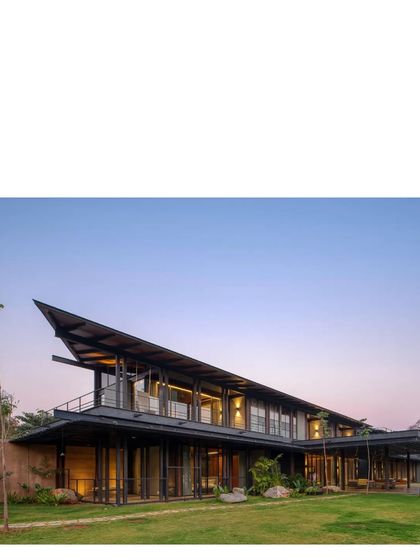 The house at dusk, with its warm interior lights glowing. The structure is designed to be a welcoming beacon in the vast landscape.