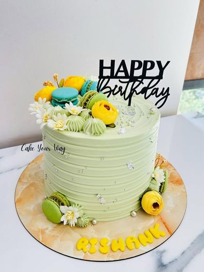 Simplicity, sweetness, and style all in one. A lovely pastel green cake topped with colorful macarons.