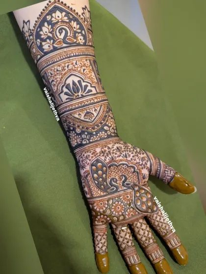 This Indian mehndi design starts with a bold peacock, flowing into beautiful lotus patterns and intricate cut-work. The contrast between the dark and light spaces makes the design pop.