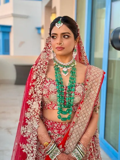 This bride in Doha wanted a look that was both traditional and striking. I paired her red lehenga with a defined eye and glowing skin, letting her magnificent emerald jewelry add a pop of contrasting color.