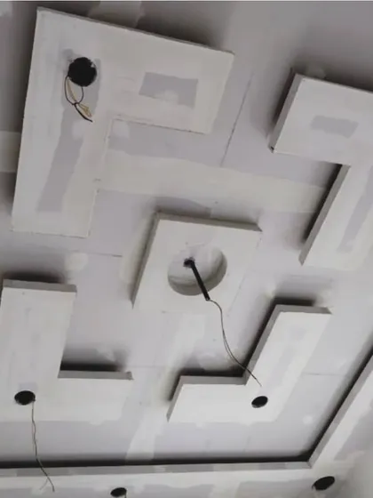 This image shows the structural build of a multi-layered geometric ceiling design. Each piece is precisely cut and installed to create a sharp, modern look before the POP finishing is applied.