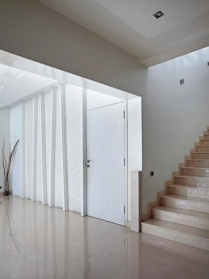 A minimalist entryway with a striking white paneled wall and a simple, elegant staircase, demonstrating the beauty of clean lines and uncluttered spaces.