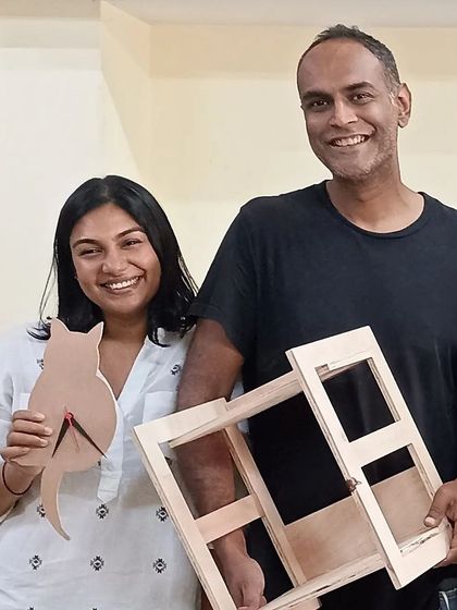 A couple showing off the cat-shaped clock and picture frame they made during a weekend workshop. These are great personalized items for the home.