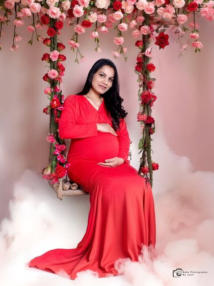 A dreamy portrait on a floral swing, surrounded by soft clouds. This is a beautiful example of a romantic and whimsical studio setup.
