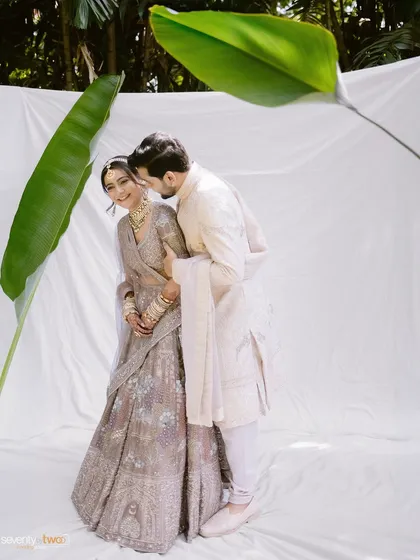 A serene and ethereal portrait. We used a simple white backdrop and a single banana leaf to create a minimal, artistic setting that highlights the couple's gentle connection.