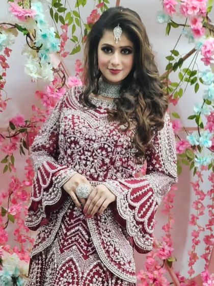 A modern and stylish reception outfit. This maroon peplum-style top with bell sleeves is paired with a matching embroidered skirt, perfect for a cocktail party.