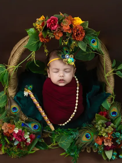 Celebrating our culture and traditions is a beautiful way to welcome your baby. This little Krishna setup, with a flute, peacock feathers, and rich colors, is a popular choice for a traditional themed baby photoshoot.
