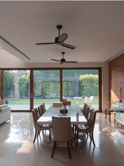 The expansive dining area seamlessly merges with the outdoors through floor-to-ceiling glass walls. This design choice floods the space with natural light and creates a constant dialogue between the interior and the lush landscape.