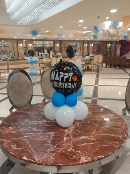 A space-themed "Happy Birthday" balloon centerpiece for a table. This is a simple way to carry the party theme onto every table in the venue.