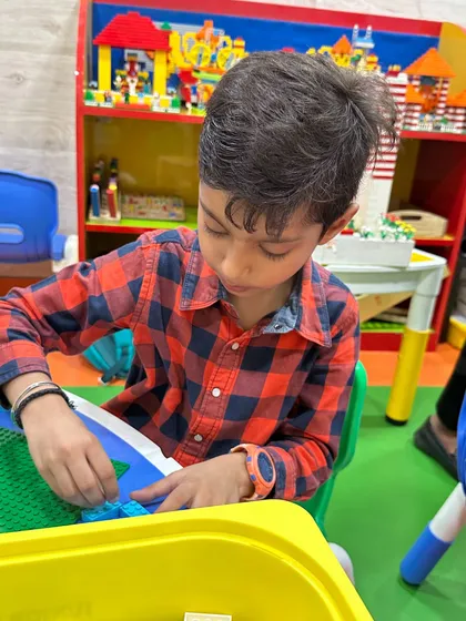 A young boy is deeply focused on his building project, selecting the right pieces for his model.