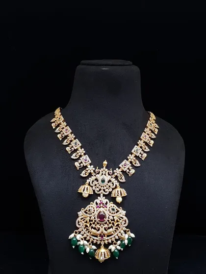 A grand necklace with a large, intricately designed pendant featuring green beads and pearls. This is a perfect statement piece for a bride or for attending a close family wedding.