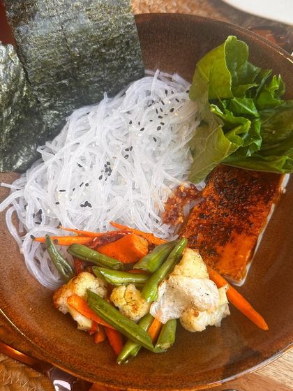 An example of a clean, balanced meal I eat while traveling. This bowl contains glass noodles, salmon, and fresh vegetables, proving you can eat healthy anywhere.