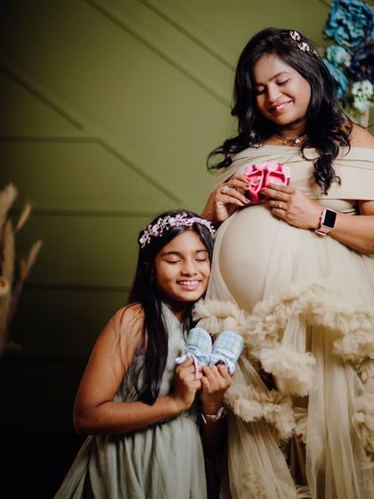 This is a lovely shot for a family expecting their second child. The mom-to-be and her daughter are holding up tiny baby shoes, one pink and one blue, in anticipation of the new arrival.