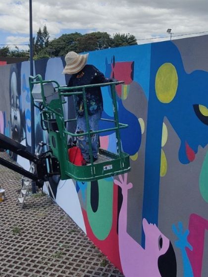 An artist working on a lift to complete the large-scale festival mural.