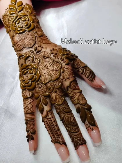 A close-up of the intricate floral and leaf work on this practice hand. The combination of bold flowers and delicate, shaded leaves creates a rich texture.