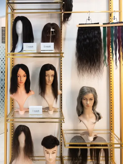 A display of various wigs and hair extensions at our studio. We offer solutions for everyone, including different lengths, colors, and styles, all made from 100% real human hair.