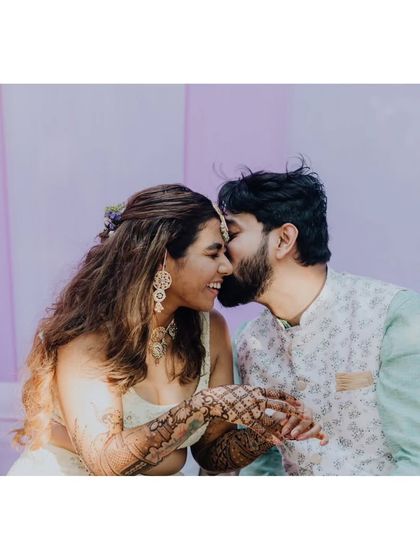 A sweet and intimate moment between the couple during their Mehendi, with the groom whispering in the bride's ear.