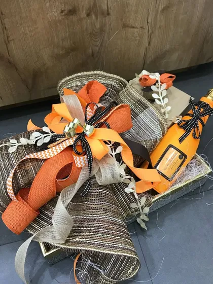 A rustic yet refined hamper featuring a vibrant orange color scheme. We've combined burlap-textured ribbons with bright orange accents and a decorative bottle, creating a gift that is perfect for a daytime celebration or a countryside wedding.