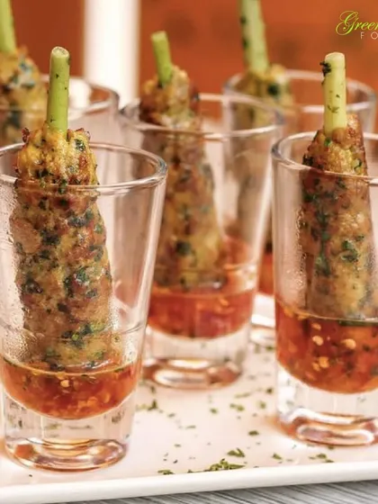 These delicious vegetable seekh kebabs are served in shot glasses with a spicy dipping sauce. This presentation is not only stylish but also practical for guests at a standing or mingling event.