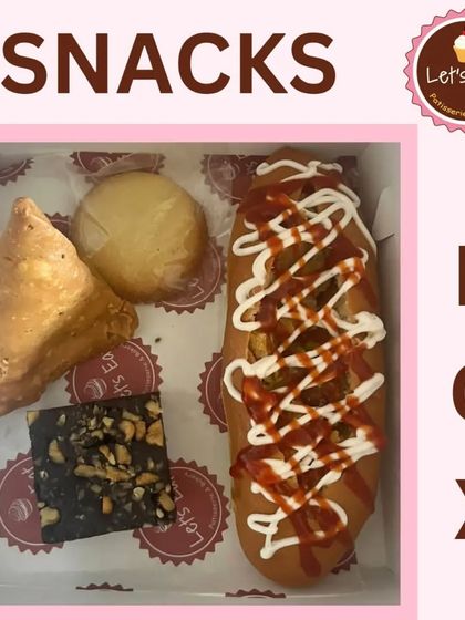 This snack box features a mix of hearty items including a samosa, a brownie, a cookie, and a hot dog, perfect for a party or casual corporate event.