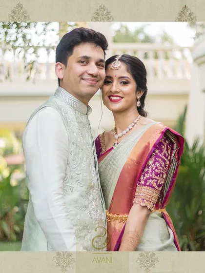 A couple portrait where the bride wears a light green saree with a contrasting magenta blouse. The blouse is heavily embroidered, creating a vibrant and festive look.