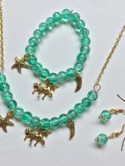 Another angle of the green beaded jewellery set, highlighting the golden unicorn, starfish, and moon charms.