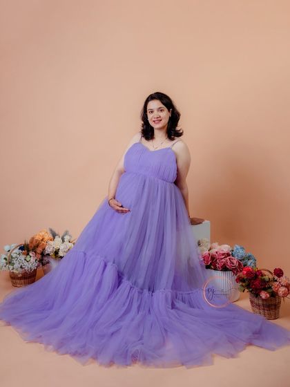 A beautiful seated portrait in a dreamy lavender tulle gown. The floor is scattered with flowers, creating a whimsical and romantic scene.