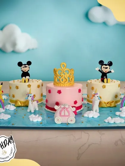 A grand celebration setup featuring multiple cakes with Mickey Mouse, unicorns, and a princess crown. This is perfect for a big party with a variety of magical themes.
