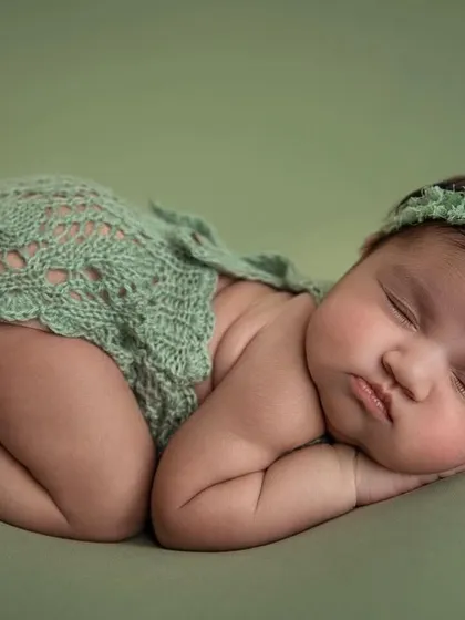 A side lying pose in a delicate green lace romper. This pose is perfect for showing off the baby's sweet back rolls.