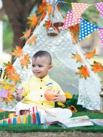 A happy baby boy enjoying his first birthday setup with a colorful teepee.
