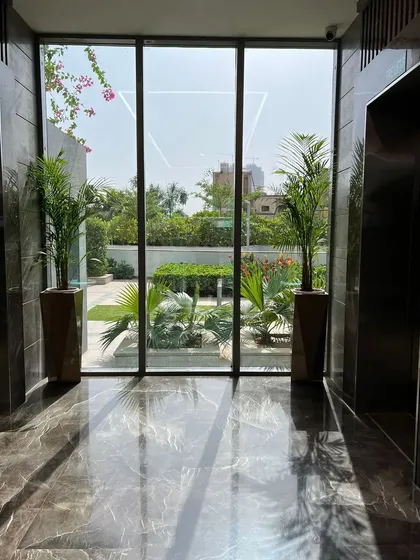 We frame views and soften modern architecture with carefully placed plants. These two palms in an elevator lobby create a beautiful transition between the sleek interior and the lush garden visible outside.