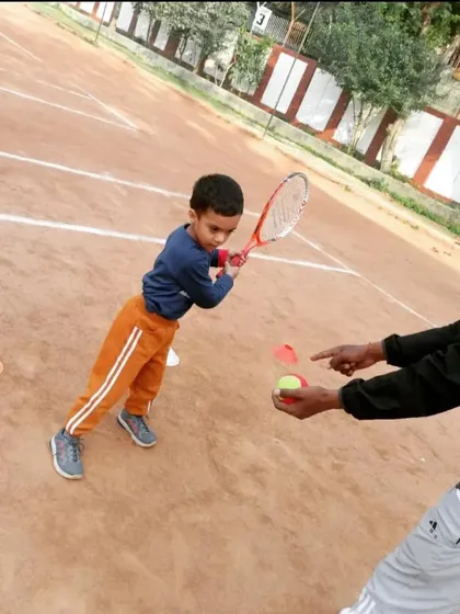 A coach demonstrating the contact point for a forehand shot to a young student. Visual cues are very important for beginners.