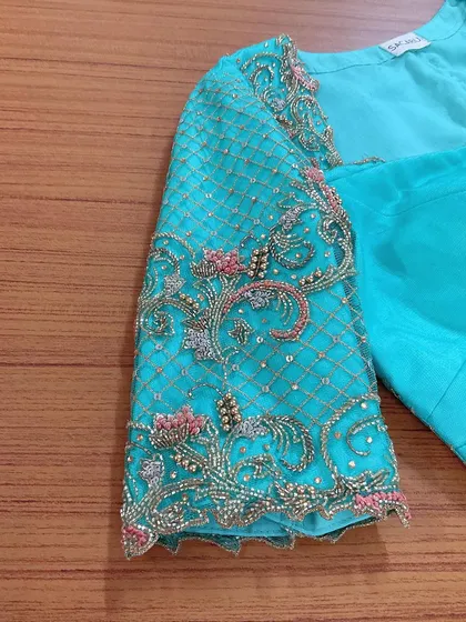 A close-up of the sleeve of our turquoise blouse, showcasing the intricate zardosi work in a lattice pattern.