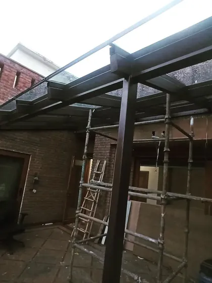 A wide shot of the construction site for a glass extension. Even with scaffolding and tools present, the final form of the beautiful, transparent space is beginning to emerge.